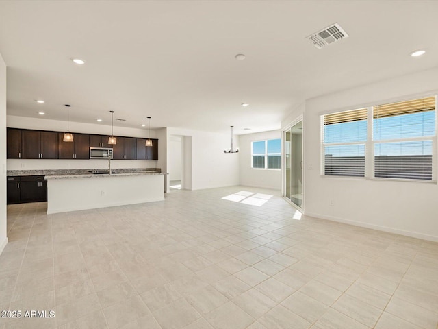 unfurnished living room with sink, an inviting chandelier, and light tile patterned floors