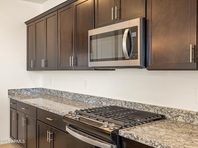 kitchen featuring appliances with stainless steel finishes, dark brown cabinets, and light stone counters