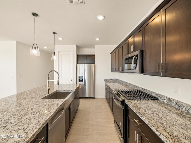 kitchen with light stone countertops, hanging light fixtures, sink, stainless steel appliances, and dark brown cabinetry