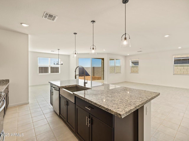 kitchen featuring sink, pendant lighting, a center island with sink, and light tile patterned floors