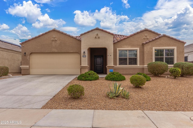 mediterranean / spanish house with a garage, concrete driveway, a tiled roof, and stucco siding