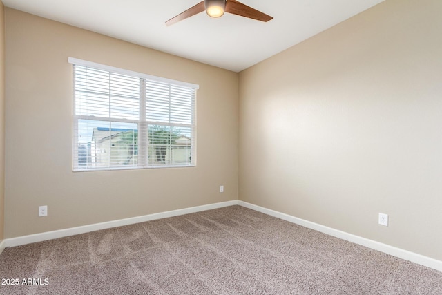 carpeted spare room featuring a ceiling fan and baseboards