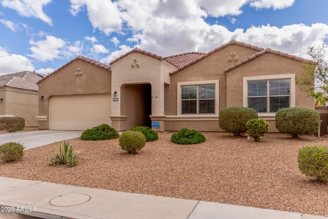 mediterranean / spanish-style home with concrete driveway, an attached garage, a tile roof, and stucco siding