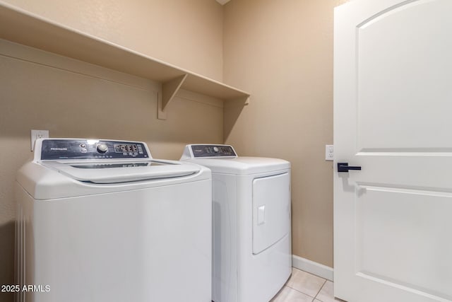 washroom with light tile patterned floors, laundry area, independent washer and dryer, and baseboards