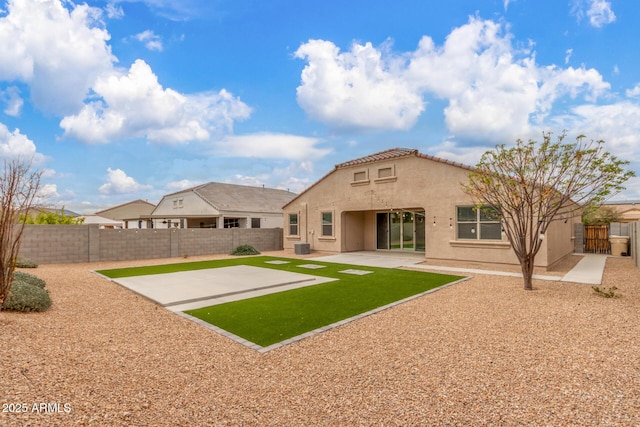 back of house featuring a fenced backyard, a tile roof, a lawn, stucco siding, and a patio area