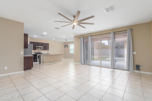 unfurnished living room featuring light tile patterned floors, baseboards, visible vents, and a ceiling fan