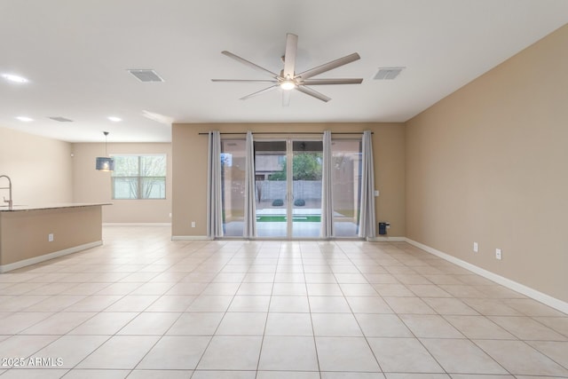 spare room featuring light tile patterned floors, a ceiling fan, visible vents, and baseboards