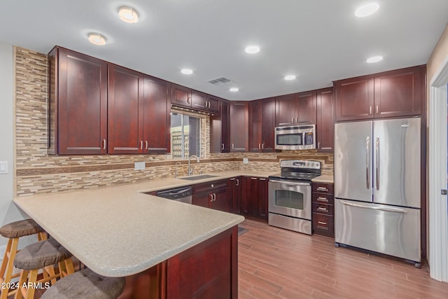 kitchen with a kitchen breakfast bar, kitchen peninsula, sink, and appliances with stainless steel finishes