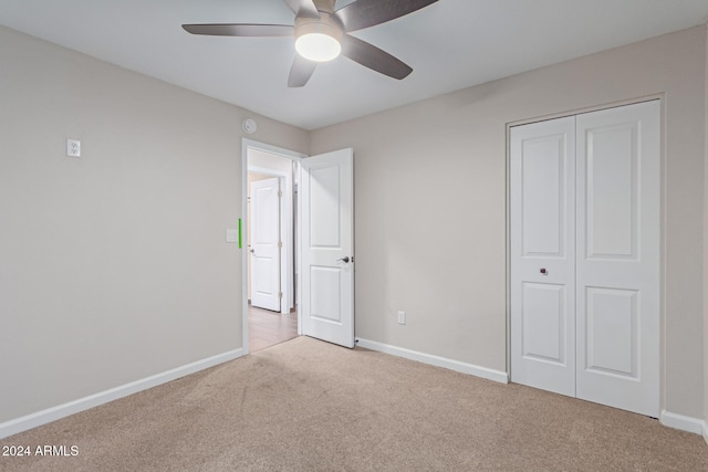 unfurnished bedroom with ceiling fan, light carpet, and a closet