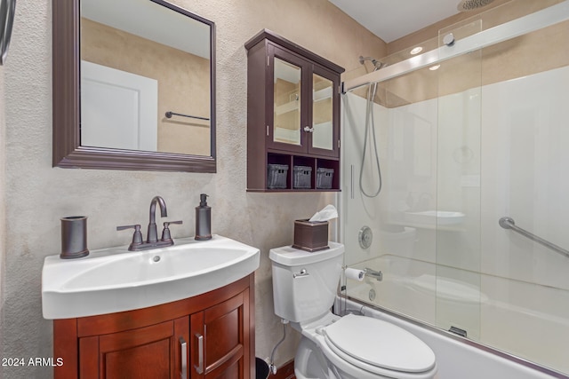 full bathroom featuring vanity, bath / shower combo with glass door, and toilet