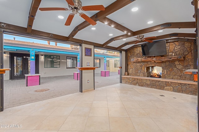 interior space with ceiling fan, lofted ceiling with beams, a kitchen bar, a fireplace, and light tile patterned floors