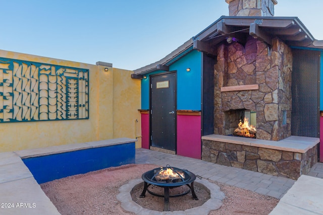 view of patio with a fire pit and an outdoor stone fireplace