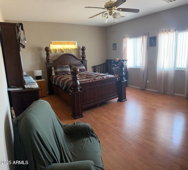 bedroom with visible vents, baseboards, ceiling fan, and wood finished floors