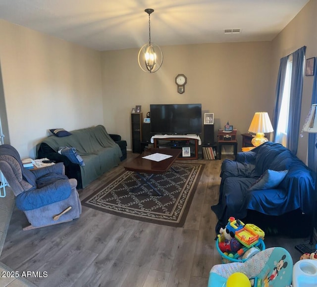 living room featuring visible vents, a notable chandelier, and wood finished floors