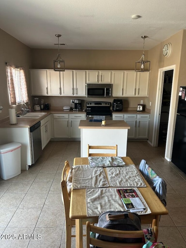 kitchen featuring a sink, hanging light fixtures, light tile patterned floors, and stainless steel appliances