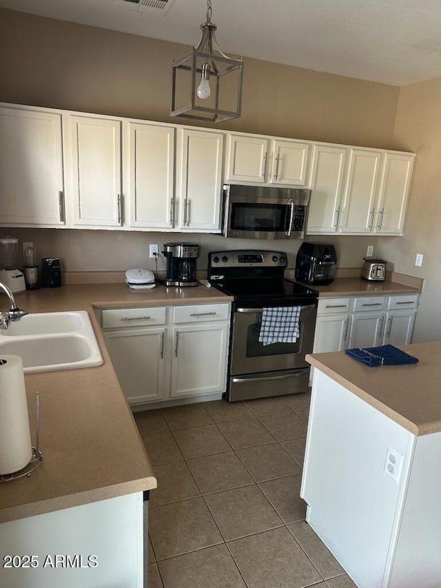 kitchen featuring a sink, stainless steel appliances, light tile patterned floors, and white cabinetry