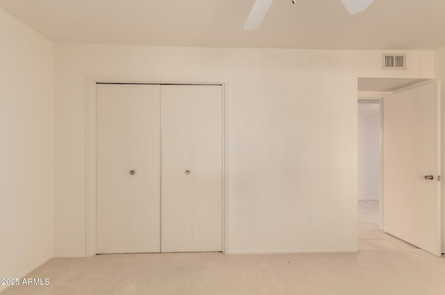 unfurnished bedroom featuring light carpet, a closet, and ceiling fan