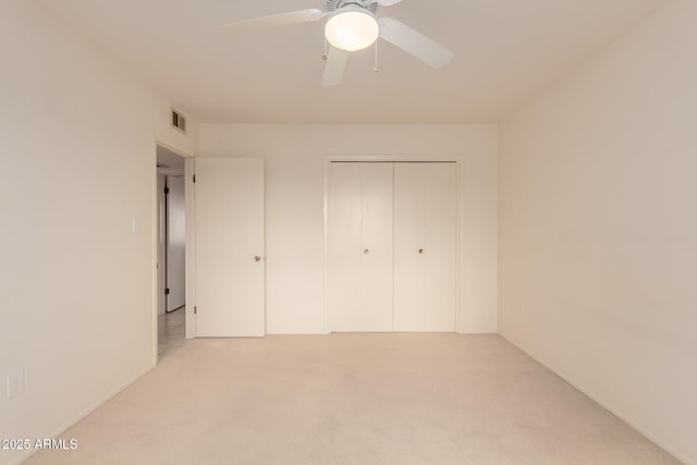 unfurnished bedroom featuring light colored carpet, a closet, and ceiling fan