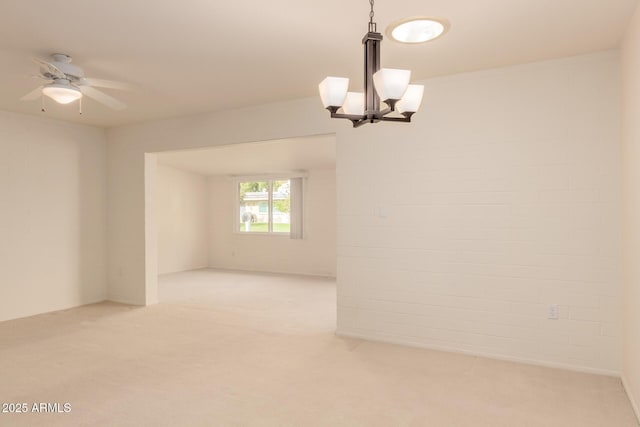 carpeted spare room with brick wall and ceiling fan with notable chandelier