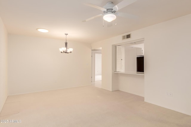 carpeted empty room featuring ceiling fan with notable chandelier