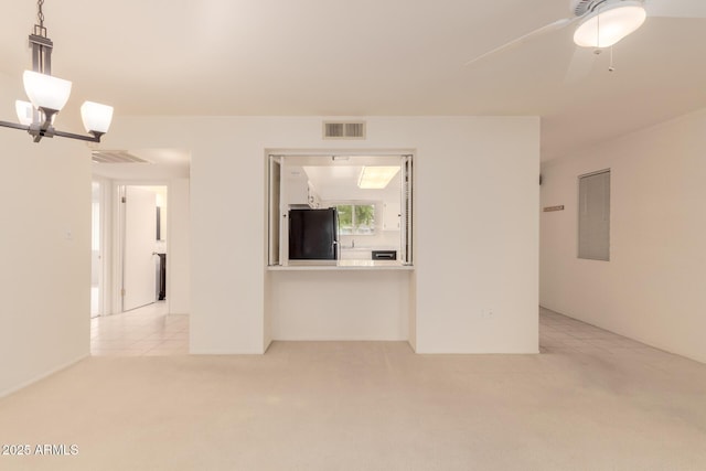 unfurnished living room featuring ceiling fan with notable chandelier and light colored carpet