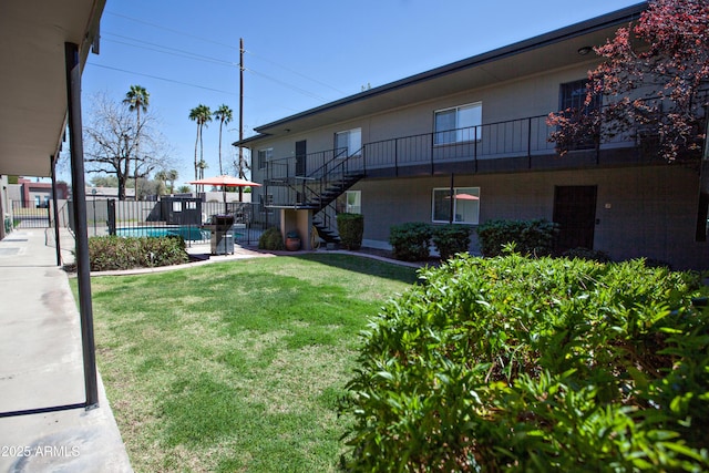 view of yard with fence, a fenced in pool, and stairs
