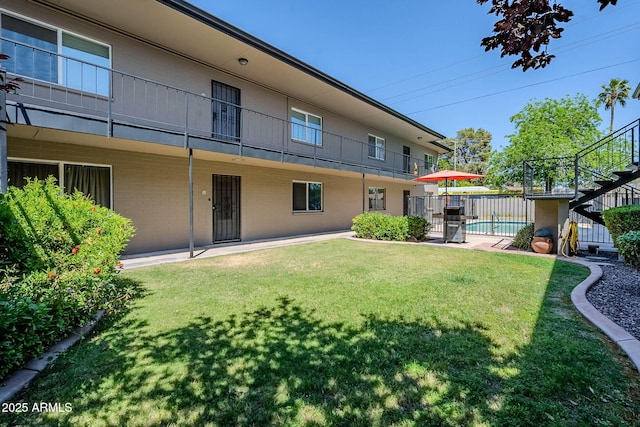exterior space featuring fence, a yard, a fenced in pool, and a balcony
