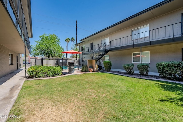 view of yard with stairway, a fenced in pool, and fence