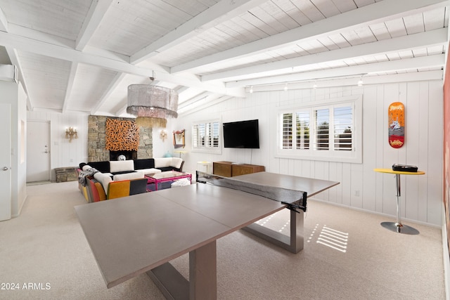 recreation room featuring a stone fireplace, lofted ceiling with beams, light carpet, and wood walls