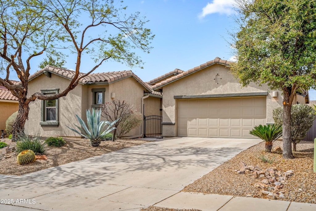 11725 N Sage Brook Rd, Tucson, AZ 85737 - view of front of house featuring a tile roof, a gate, concrete driveway, stucco siding, and a garage