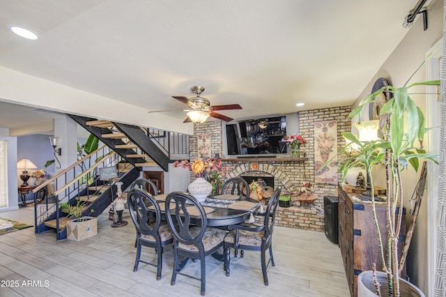 4112 E Maldonado Dr, Phoenix, AZ 85042 - dining space with a brick fireplace, brick wall, a ceiling fan, wood finished floors, and stairs