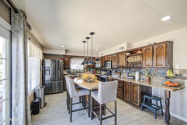 4112 E Maldonado Dr, Phoenix, AZ 85042 - kitchen featuring tasteful backsplash, visible vents, a breakfast bar, stainless steel appliances, and light wood-style flooring