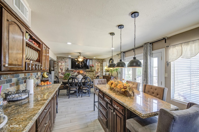 4112 E Maldonado Dr, Phoenix, AZ 85042 - kitchen with visible vents, decorative light fixtures, ceiling fan, a breakfast bar, and a textured ceiling
