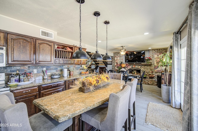 4112 E Maldonado Dr, Phoenix, AZ 85042 - kitchen with white microwave, visible vents, a brick fireplace, a breakfast bar area, and ceiling fan