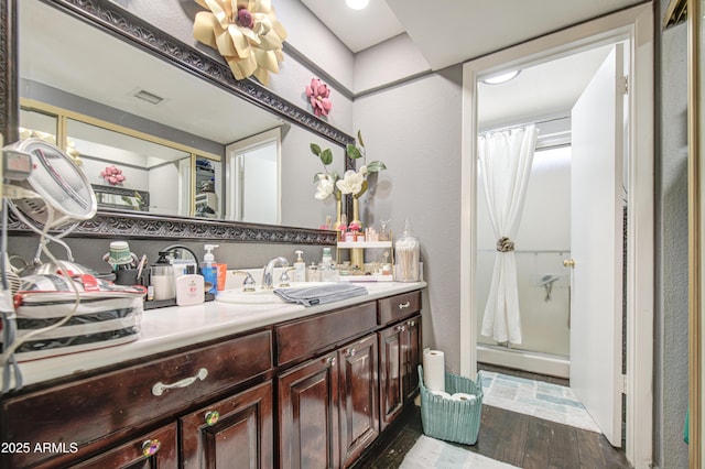 4112 E Maldonado Dr, Phoenix, AZ 85042 - full bath with a shower with shower curtain, vanity, a textured wall, visible vents, and wood finished floors