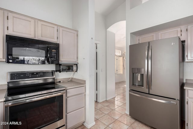 kitchen featuring light tile patterned floors, stainless steel appliances, and high vaulted ceiling