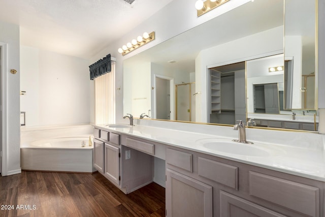 bathroom with hardwood / wood-style floors, vanity, and shower with separate bathtub