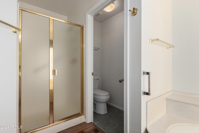 bathroom featuring tile patterned floors, a shower with shower door, and toilet