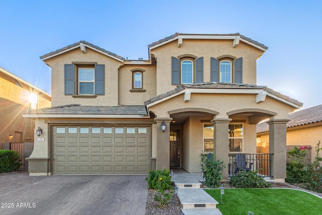 view of front of house with a garage, decorative driveway, a tile roof, and stucco siding