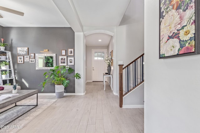 entryway with stairway, baseboards, arched walkways, and wood finished floors