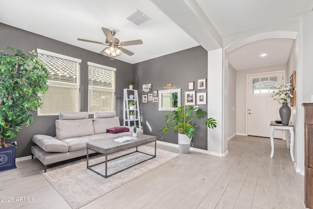 living area featuring light wood-style flooring, visible vents, ceiling fan, and baseboards