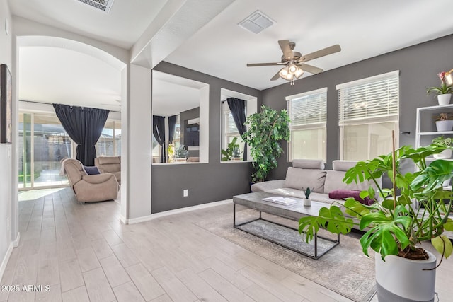 interior space featuring baseboards, visible vents, a ceiling fan, arched walkways, and wood finished floors