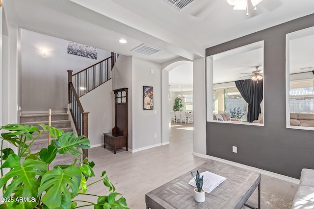 living room with a ceiling fan, a wealth of natural light, visible vents, and wood finished floors