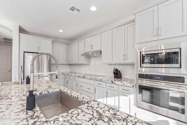 kitchen featuring appliances with stainless steel finishes, visible vents, a sink, and under cabinet range hood