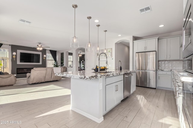 kitchen with arched walkways, stainless steel appliances, a sink, and visible vents