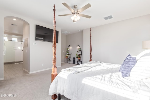 carpeted bedroom featuring baseboards, visible vents, arched walkways, and a ceiling fan