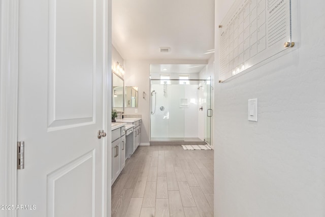 full bath with wood finished floors, vanity, visible vents, baseboards, and a stall shower