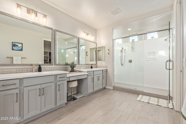 bathroom with visible vents, backsplash, a stall shower, vanity, and wood finished floors