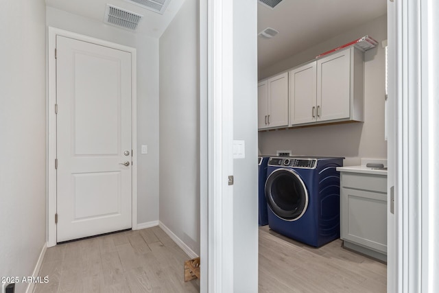 laundry room featuring washer / dryer, cabinet space, visible vents, baseboards, and light wood-style flooring