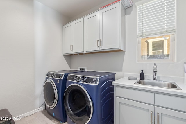 washroom with cabinet space, a sink, baseboards, and separate washer and dryer